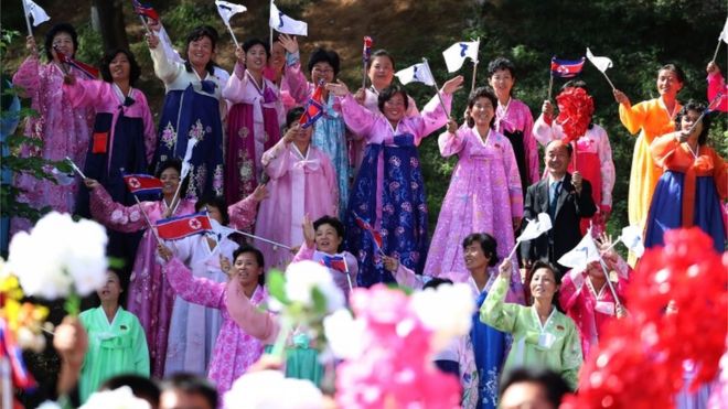 Северокорейцы в традиционном наряде размахивают флагами, чтобы приветствовать Луну Чжэ-ин в Пхеньяне
