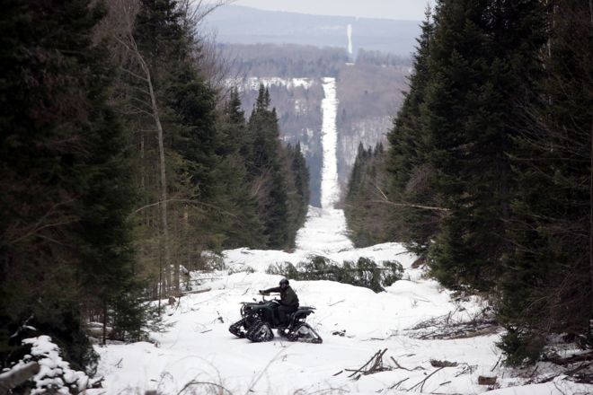 Агент пограничного патрулирования США Эндрю Майер едет на квадроцикле, разыскивая признаки нелегального въезда вдоль границы, вырубленной в лесу, отмечающем линию между канадской территорией справа и Соединенными Штатами 23 марта 2006 года около Бичер-Фолс, штат Вермонт.