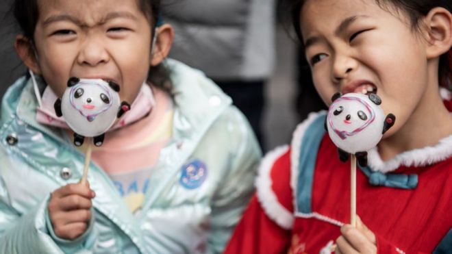 Two girls lick sugar figurine in the likes of Beijing 2022 Winter Olympic mascot Bing Dwen Dwen during the celebration of the Lantern Festival which marks the end of Lunar New Year celebrations.