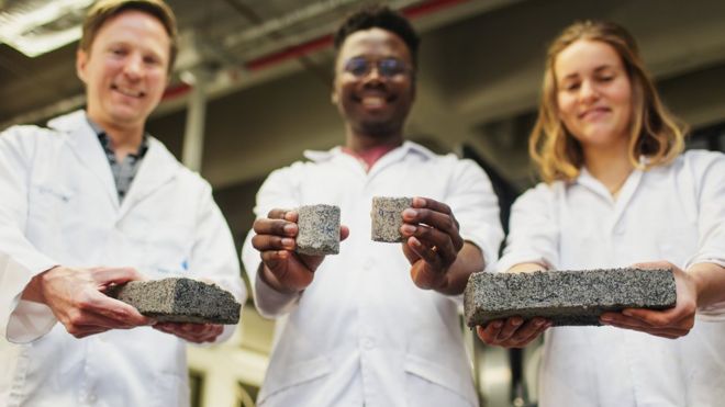 Dyllon Randall com seus estudantes, Vukheta Mukhari e Suzanne Lambert, segurando um biotijolo