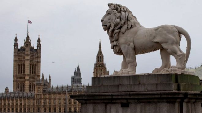 A statue of a lion stands over the River Thames from the Houses of Parliament in London, 25 October 2019