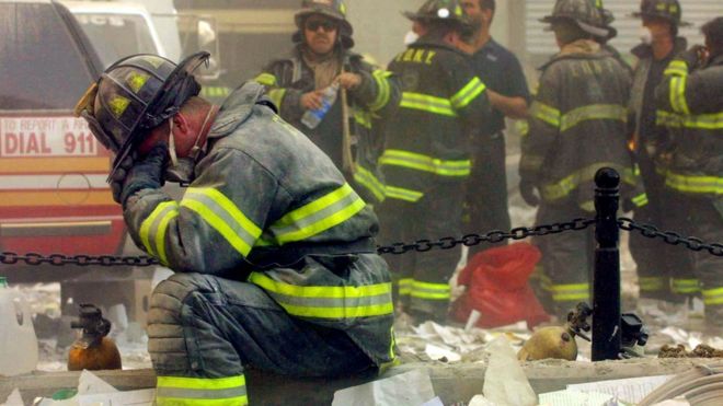 Firefighter pauses in rubble on World Trade Center (9/11/01)