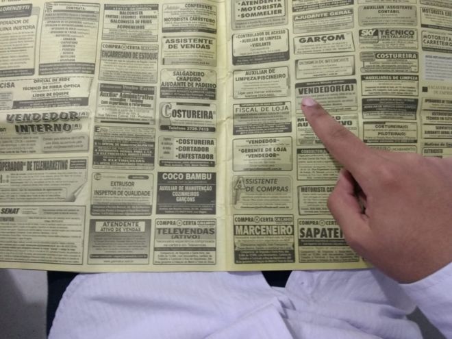 Imagem mostra mão apontando para vaga de emprego nos classificados do jornal