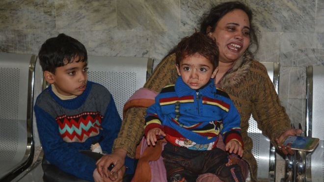 Женщина плачет, когда она сидит с двумя маленькими мальчиками, один окровавленный, на скамейке после нападения в Кветте (17 декабря 2017 года)
