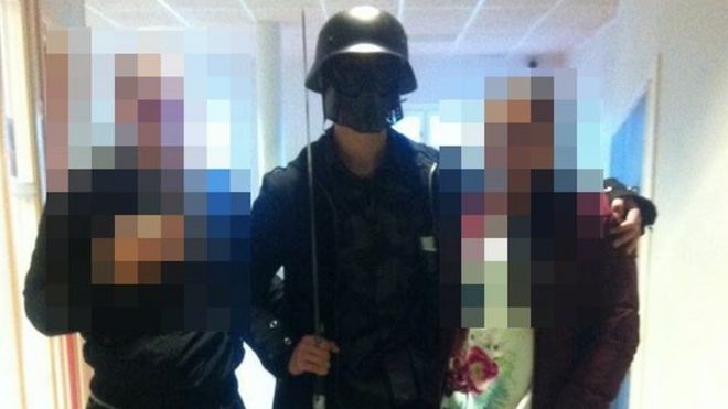 На этой фотографии, предоставленной AFP студентом, мужчина в маске, вооруженный мечом, позирует для фотографии с двумя другими студентами перед тем, как напасть на студентов и сотрудников в Трольхеттане, юго-западная Швеция, 22 октября 2015 года.