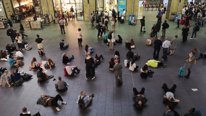 Люди ждут на вокзале Кингс-Кросс в Лондоне, так как все услуги на станции и из нее были приостановлены после того, как из-за сильного отключения электричества