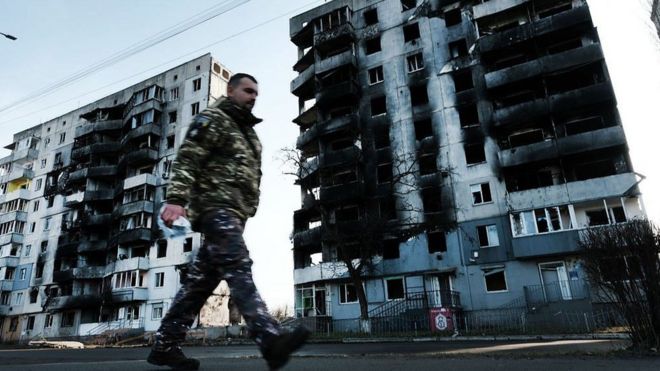 Украинский военный на фоне разрушенного здания