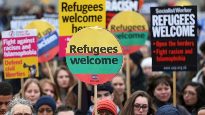 Демонстранты держат плакаты во время приветственного марша беженцев в Лондоне