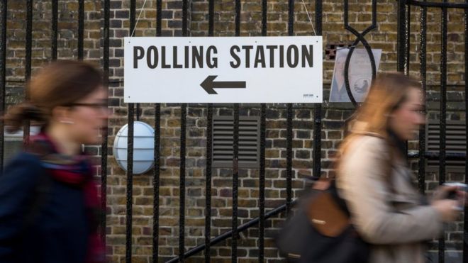 Two women walk past a polling station