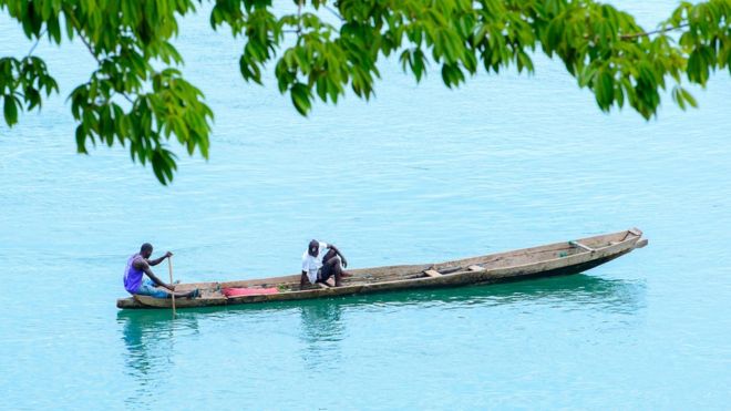 Мужчины гребут на лодке у побережья Биджагос