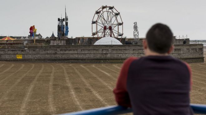 Человек смотрит на пляж в сторону Dismaland