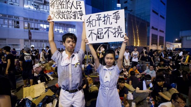 Демонстранты средней школы держат таблички во время акции протеста перед зданием Законодательного совета в Гонконге 29 сентября 2014 года