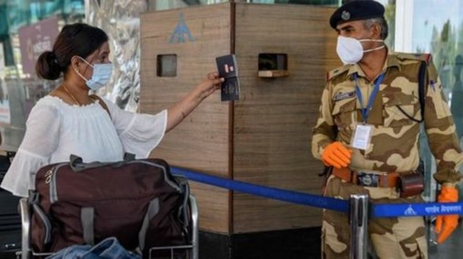 Una mujer le muestra el pasaporte a un guardia de seguridad en un aeropuerto