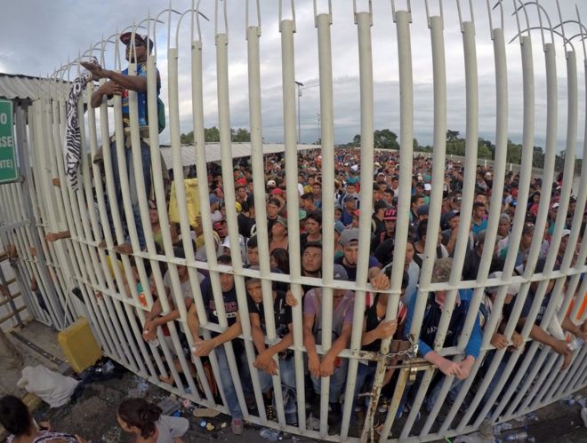 Гондурасские мигранты ждут за воротами после пересечения забора на границе с Гватемалой, чтобы въехать в Мексику