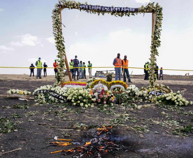 Свечи горят до того, как 14 марта 2019 года в Эджере, Эфиопия, на месте крушения рейса ET302 эфиопских авиалиний была установлена ??украшенная цветами мемориальная арка.