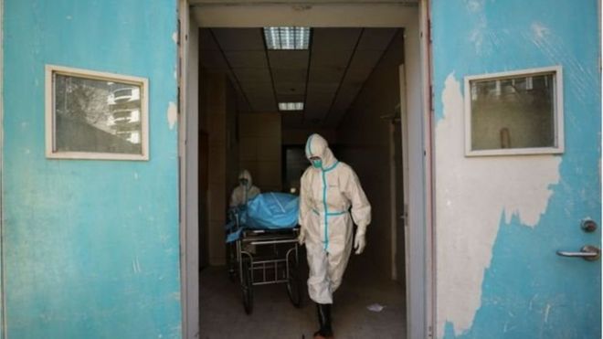 Médicos carregam paciente morto pelo coronavírus na China