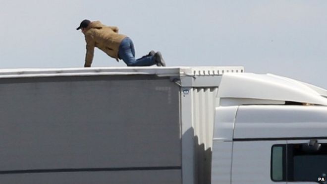 Фото из архива, датированное 24/06/15 мигрантом, пытающимся сесть на грузовик, связанный с Великобританией, на главной дороге в паромный порт Кале