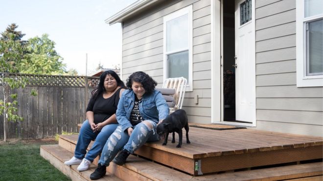 Sherry Mesa (E) e sua sobrinha, Sobeyda (D), sentadas em frente à microcasa em que vivem desde julho no quintal de Martha Chambers, nos EUA. Elas antes eram sem-teto