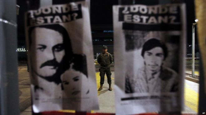 Две фотографии людей, пропавших без вести во время правления Пиночета в Чили, висят возле военного госпиталя