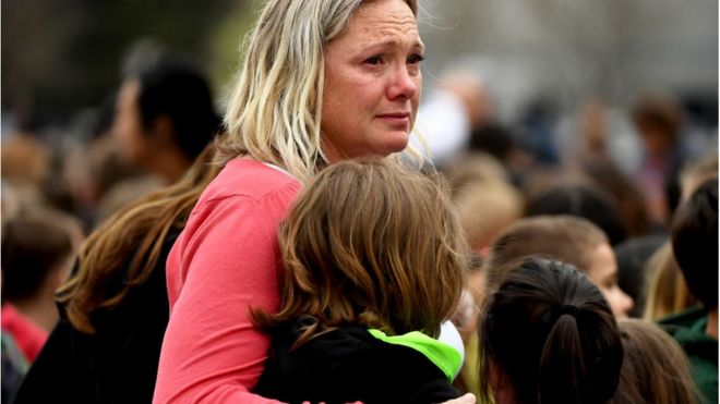 Сотрудник школы утешает ребенка после стрельбы