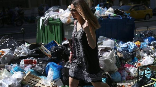 A woman walks through rubbish in Athens