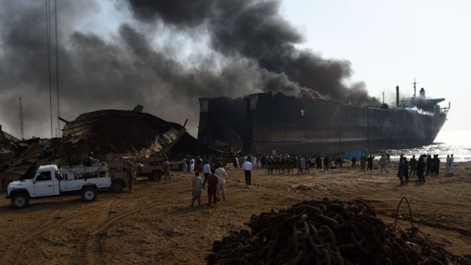 Pakistani bystanders gather around the wreckage of a burning ship after a gas cylinder explosion at the Gadani shipbreaking yard, some 50 kilometres (30 miles) west of Karachi on 1 November, 2016