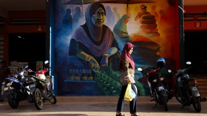 Mulher caminha em frente a mural no mercado central de Siti Khadijah em Kota Bharu