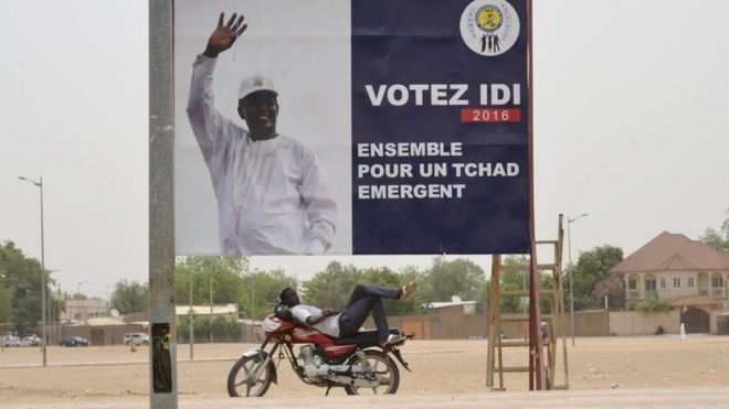 A man resting under a campaign poster of Chad's President Idriss Deby in N'Djamena on 12 April 2016