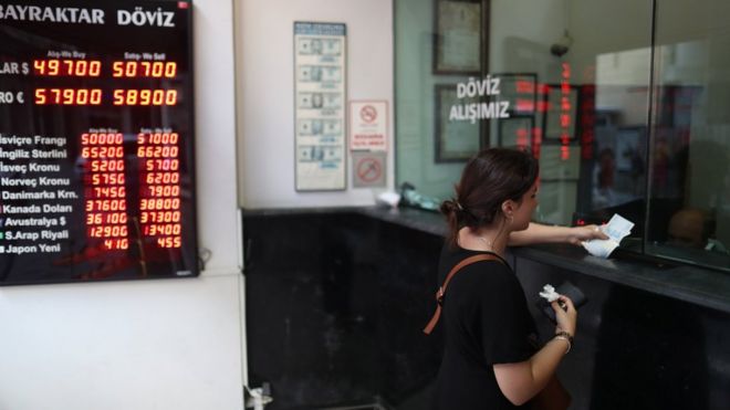 Женщина обменивает деньги в обменном пункте в Стамбуле, Турция.