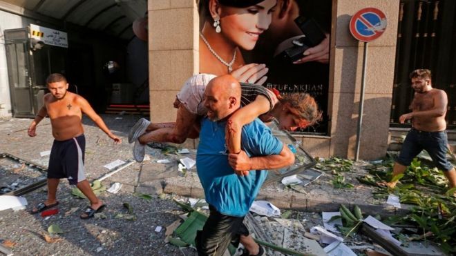 Un hombre porta a una joven herida por la explosión en Beirut.