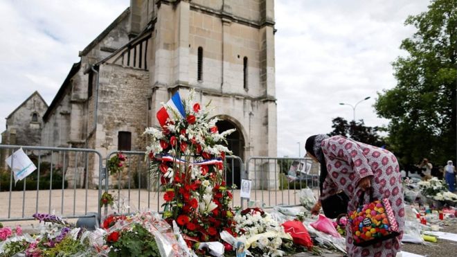Мусульманка возлагает цветы перед церковью Сент-Этьен-дю-Рувр, западная Франция, где 26 июля (29 июля 2016 года) был убит французский священник Жак Амель.