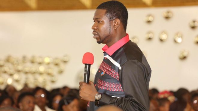 Walter Magaya speaks to a congregation whose faces are blurred