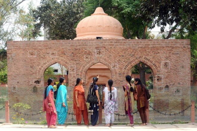 Индийские посетители смотрят на обстрелянную пулями стену в историческом месте резни в Джаллианвала Багхе в Амритсаре 12 апреля 2011 года