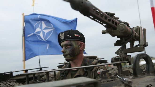 Polşalı əsgər NATO bayrağının önündə