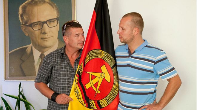 Dos hombres sostienen la bandera de la antigua República Democrática Alemana (RDA)