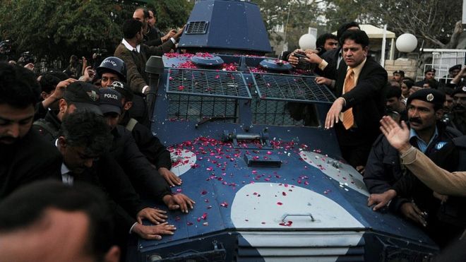 Пакистанская полиция сопровождает бронированный автомобиль с арестованным пакистанским телохранителем Маликом Мумтазом Хуссейном Кадри, предполагаемым убийцей губернатора Пенджаба Салмана Тасира, когда они покидают антитеррористический суд после слушания в Равалпинди 6 января 2011 года.