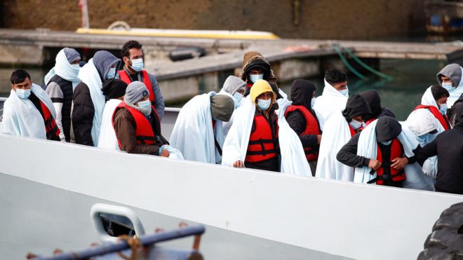 Migrants wait to disembark a boat the the Port of Dover