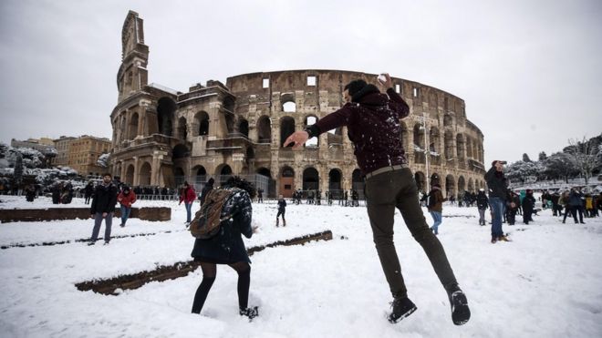 People take part in a snowball fight in front of the Colosseum covered by snow during a snowfall in Rome, Italy, 26 February 2018.