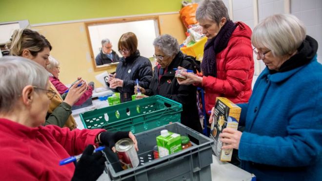 Волонтеры Foodbank сортируют пожертвования на складе перед раздачей их местным фудбанкам 28 января 2019 года в Сталибридже, Англия.