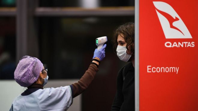 Passengers have their temperature checked by health officials as they arrive from a Qantas flight at Sydney Airport.