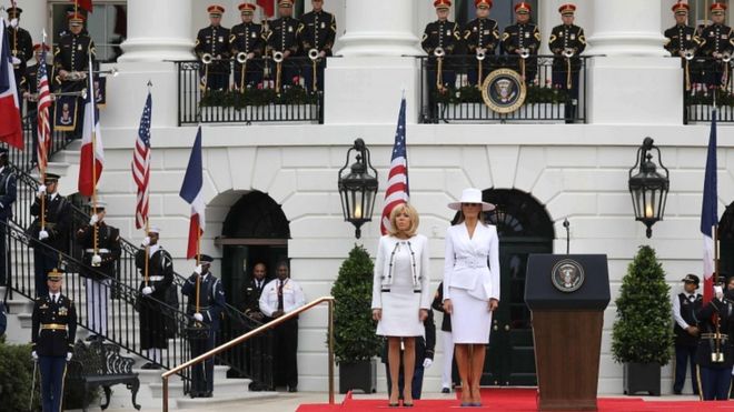 Первая леди Франции Бриджит Макрон и первая леди США Мелания Трамп (справа) стоят на трибуне во время церемонии государственного прибытия в Белый дом в Вашингтоне, округ Колумбия, 24 апреля 2018 года