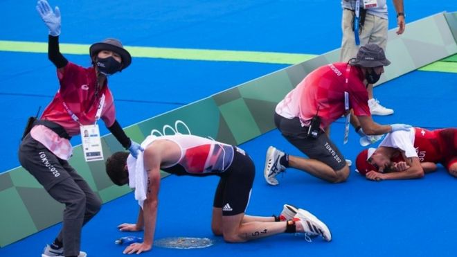 Switzerland"s Max Studer and Jonathan Brownlee of Britain are exhausted in the finish area during the men"s Individual Triathlon competition at the 2020 Tokyo Summer Olympics in Tokyo