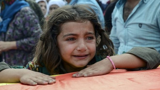 Девушка плачет, опираясь на гроб родственника, погибшего во время столкновений между турецкими войсками и РПК в городе Джизре
