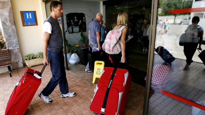 Туристы с чемоданами заходят в отель