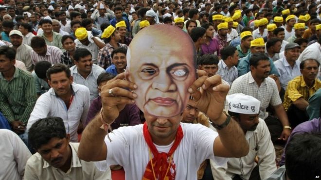 Патидар или член общины Патель держит маску индийского борца за свободу и первого министра внутренних дел Независимой Индии Сардара Валлабхбая Пателя, когда он участвует в митинге в Ахмадабаде, Индия, во вторник, 25 августа 2015 года.