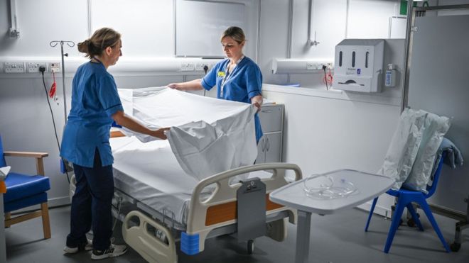 Two nurses changing hospital bed