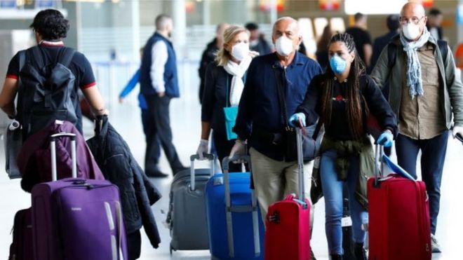 Passengers wear protective masks as they arrive at Frankfurt airport on Tuesday