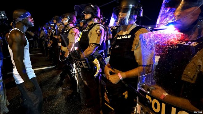 Протестующий кричит на полицейскую линию незадолго до того, как были произведены выстрелы в сотрудника полиции, причастного к стрельбе в Фергюсоне, штат Миссури, 9 августа 2015 года.