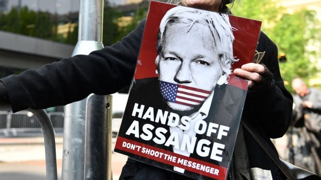 Una mujer sostiene un cartel que dice: "saquen las manos de Assange, no disparen al mensajero".