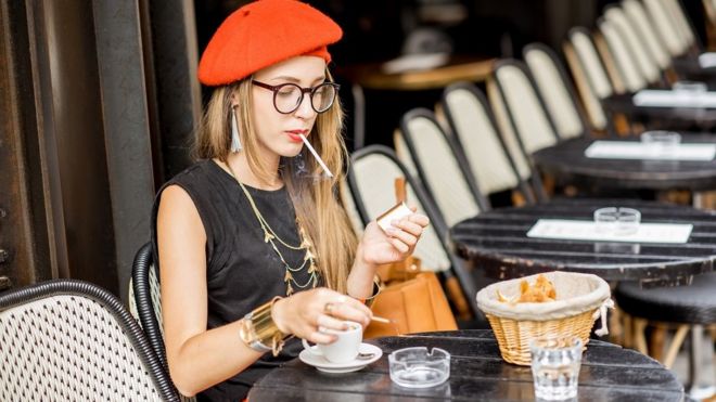 Mujer fumando en un café.